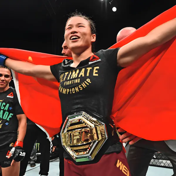 Une pratiquante d'arts martiaux mixtes joyeux célèbre sa victoire avec un drapeau rouge déployé et une ceinture de champion. La scène respire le triomphe et la fierté dans une arène.