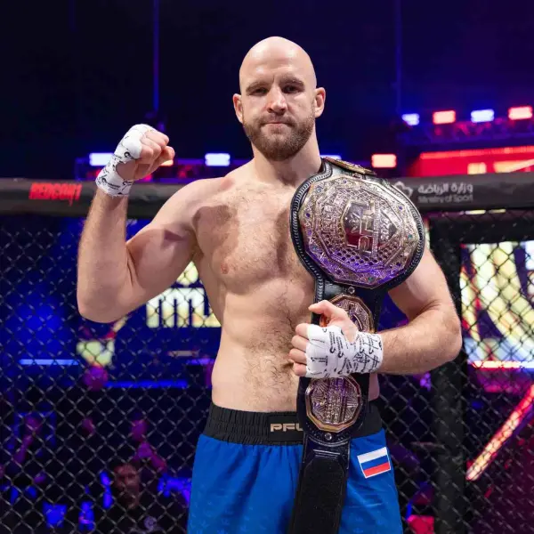 Un boxeur se tient avec assurance dans une cage, le poing levé. Il porte un short bleu et tient une ceinture de champion. Le décor est une arène colorée et illuminée.